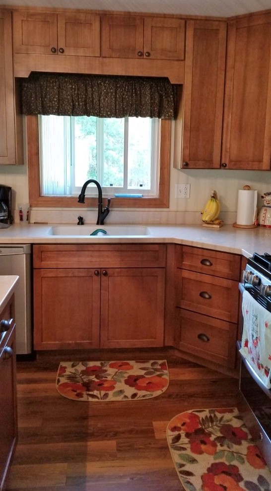 Transitional l-shaped eat-in kitchen photo with a double-bowl sink, shaker cabinets, solid surface countertops, stainless steel appliances and an island