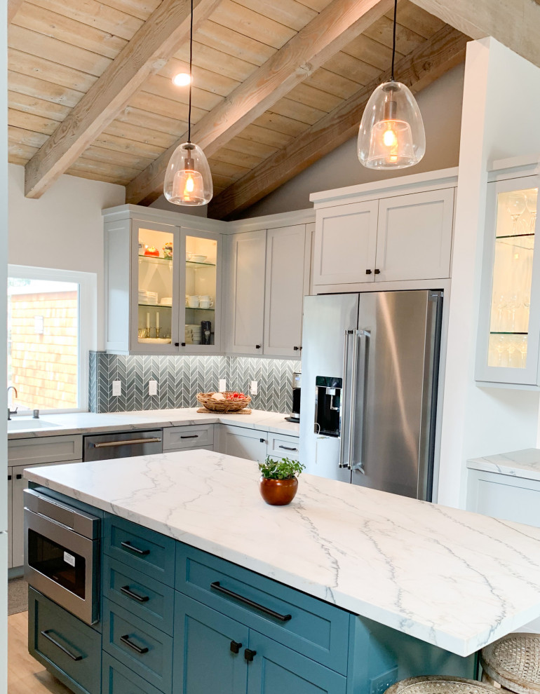 Photo of a mid-sized beach style u-shaped kitchen in Orange County with an undermount sink, shaker cabinets, turquoise cabinets, quartzite benchtops, blue splashback, glass tile splashback, stainless steel appliances, light hardwood floors, with island, multi-coloured benchtop and wood.