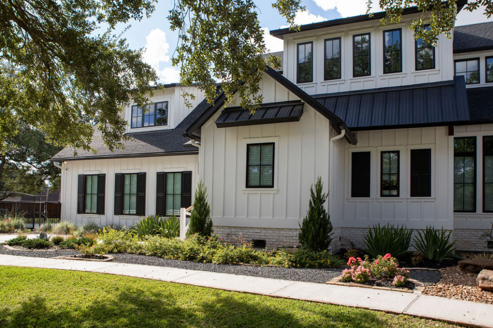 Großes, Zweistöckiges Landhaus Einfamilienhaus mit Faserzement-Fassade, weißer Fassadenfarbe, Walmdach, Misch-Dachdeckung, schwarzem Dach und Wandpaneelen in Houston