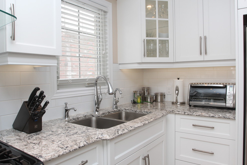 Example of a small transitional l-shaped enclosed kitchen design with an undermount sink, white cabinets, granite countertops, white backsplash, ceramic backsplash, stainless steel appliances, no island and shaker cabinets