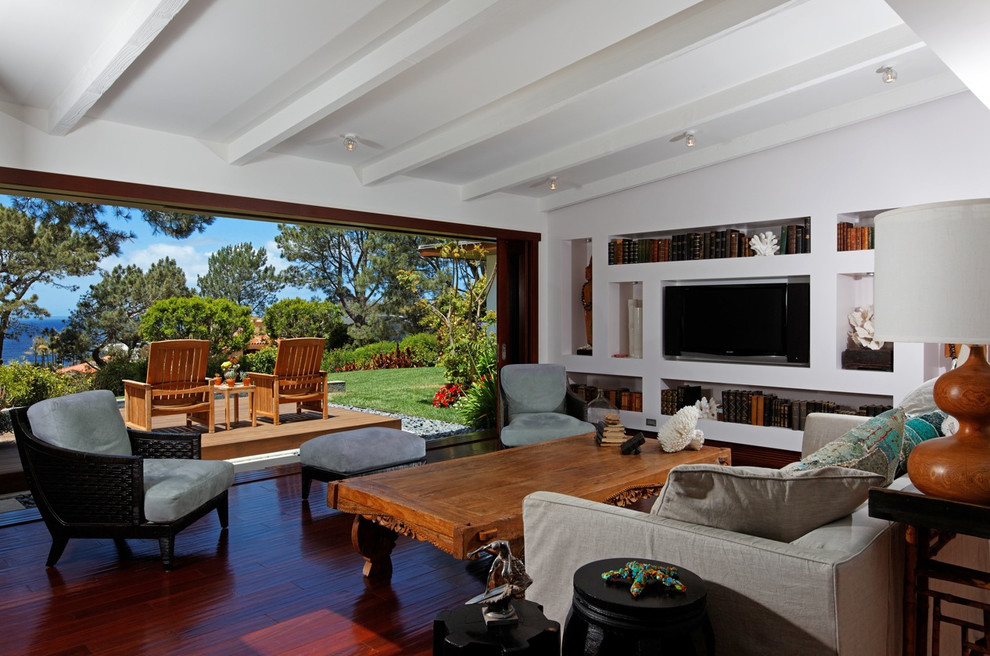 Design ideas for a tropical open concept family room in San Diego with a library, white walls, dark hardwood floors, no fireplace and a built-in media wall.