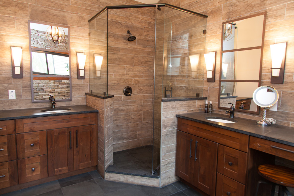 Design ideas for a large country master bathroom in St Louis with shaker cabinets, dark wood cabinets, a corner shower, brown tile, porcelain tile, slate floors, an undermount sink, soapstone benchtops, grey floor and a hinged shower door.