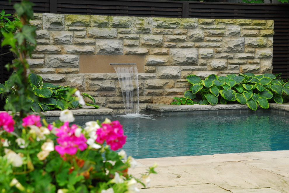 Design ideas for a mid-sized traditional backyard partial sun garden for summer in Toronto with a water feature and natural stone pavers.