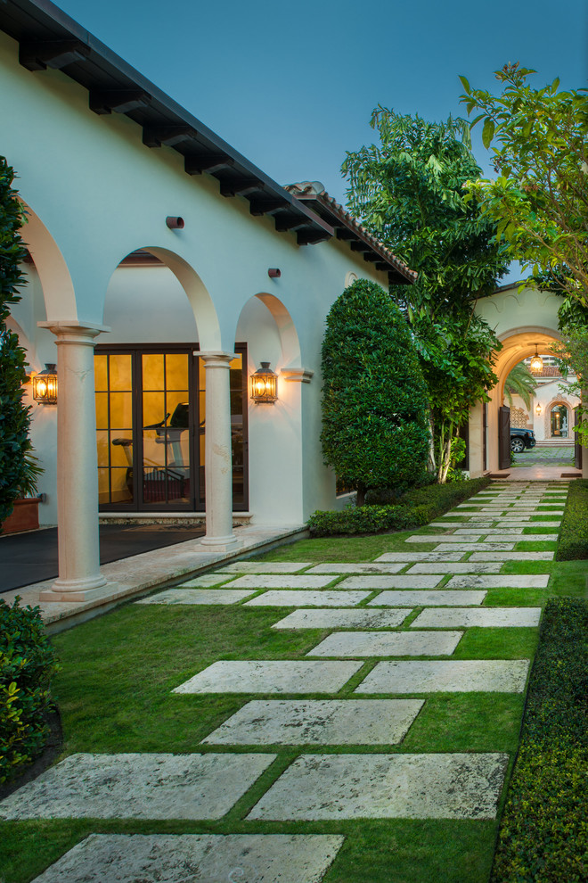This is an example of an expansive mediterranean side yard garden in Miami with a garden path and natural stone pavers.