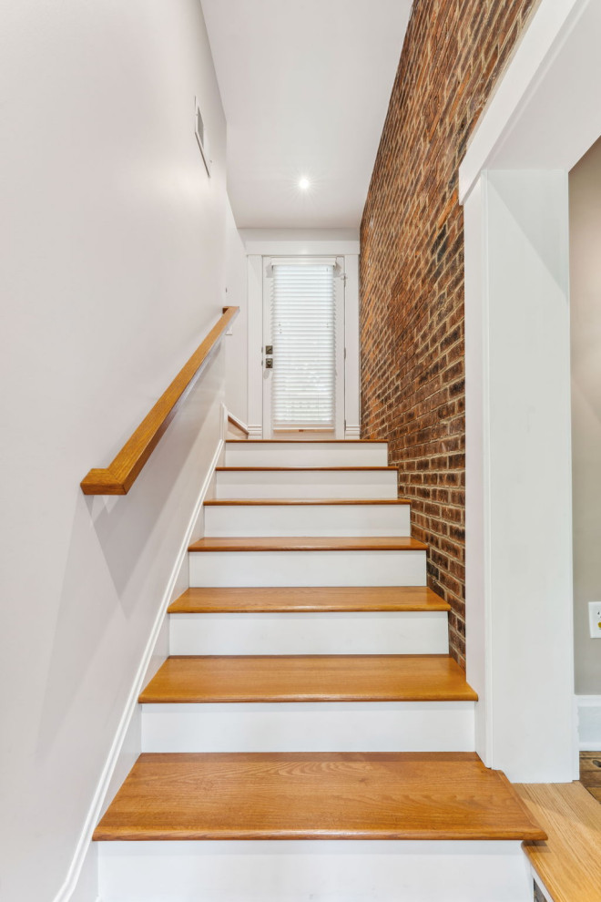 Design ideas for a mid-sized traditional wood l-shaped staircase in Columbus with painted wood risers, wood railing and brick walls.