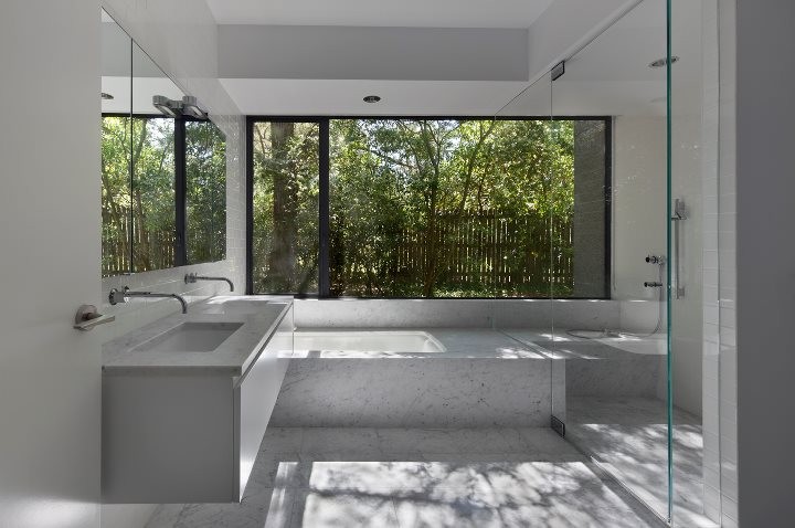 This is an example of a large modern master bathroom in Charlotte with flat-panel cabinets, white cabinets, a corner tub, a curbless shower, white tile, porcelain tile, white walls, porcelain floors, an undermount sink and quartzite benchtops.