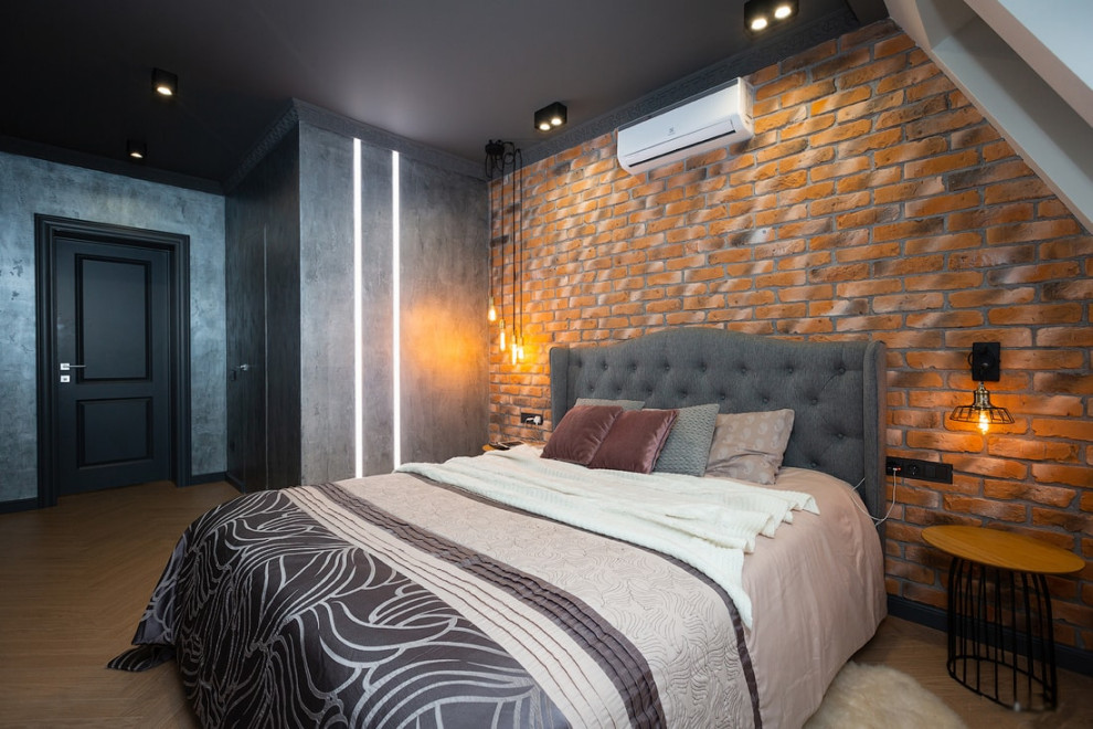 Идея дизайна: хозяйская, серо-белая спальня среднего размера в стиле лофт с коричневыми стенами, полом из ламината, коричневым полом, кирпичными стенами и акцентной стеной без камина