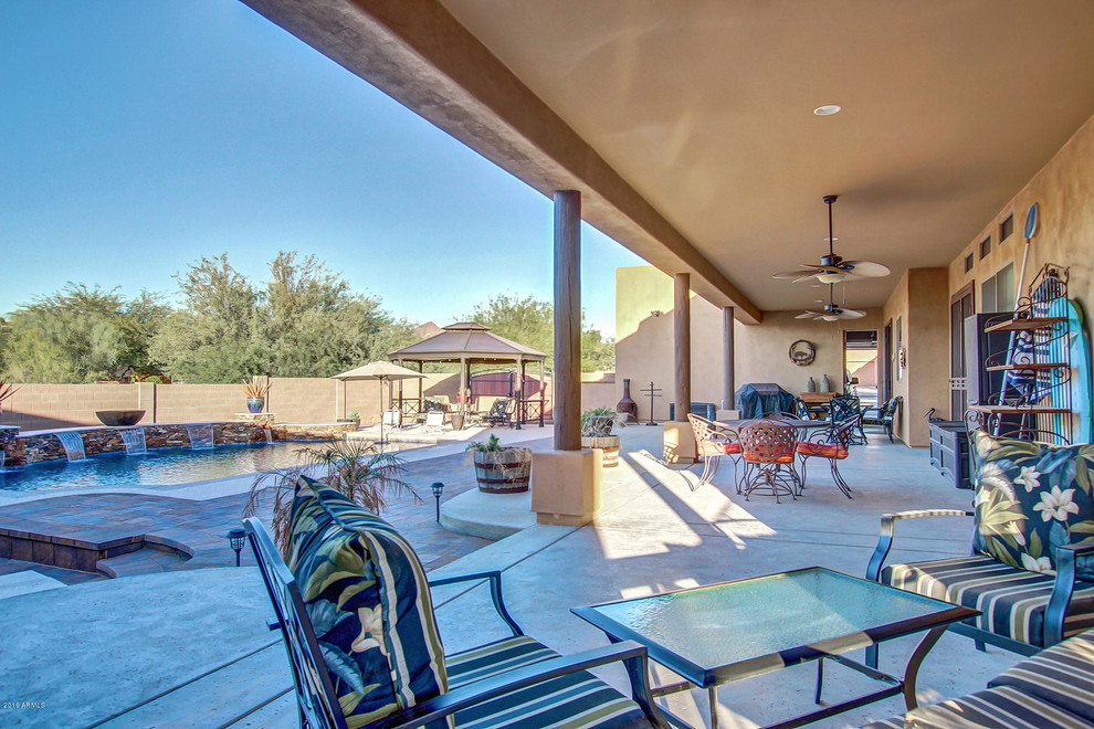 Inspiration for a large backyard patio in Phoenix with concrete pavers and a roof extension.