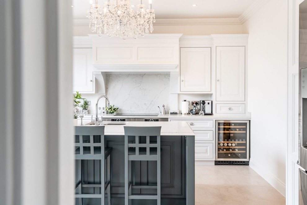 This is an example of a large traditional l-shaped kitchen in Essex with an undermount sink, raised-panel cabinets, grey cabinets, quartzite benchtops, white splashback, stainless steel appliances, porcelain floors, with island, beige floor and white benchtop.