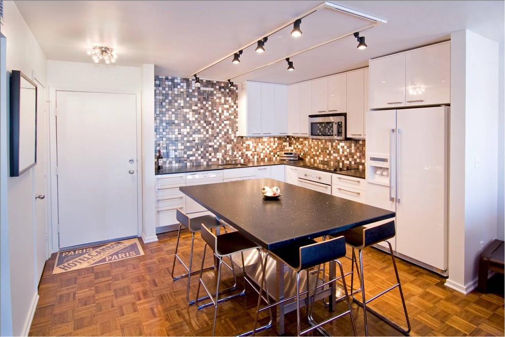 Modern l-shaped kitchen in Minneapolis with mosaic tile splashback, white appliances, brown splashback, white cabinets and flat-panel cabinets.