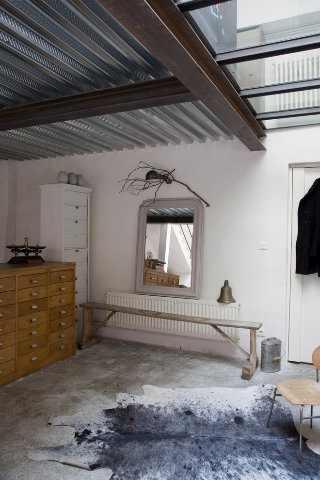 Inspiration for an industrial entryway in Paris with white walls and concrete floors.