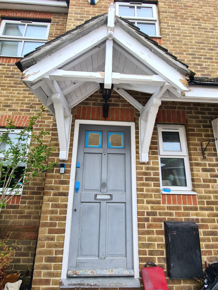 Ispirazione per una porta d'ingresso tradizionale di medie dimensioni con pavimento in cemento, una porta singola, una porta grigia e pavimento marrone