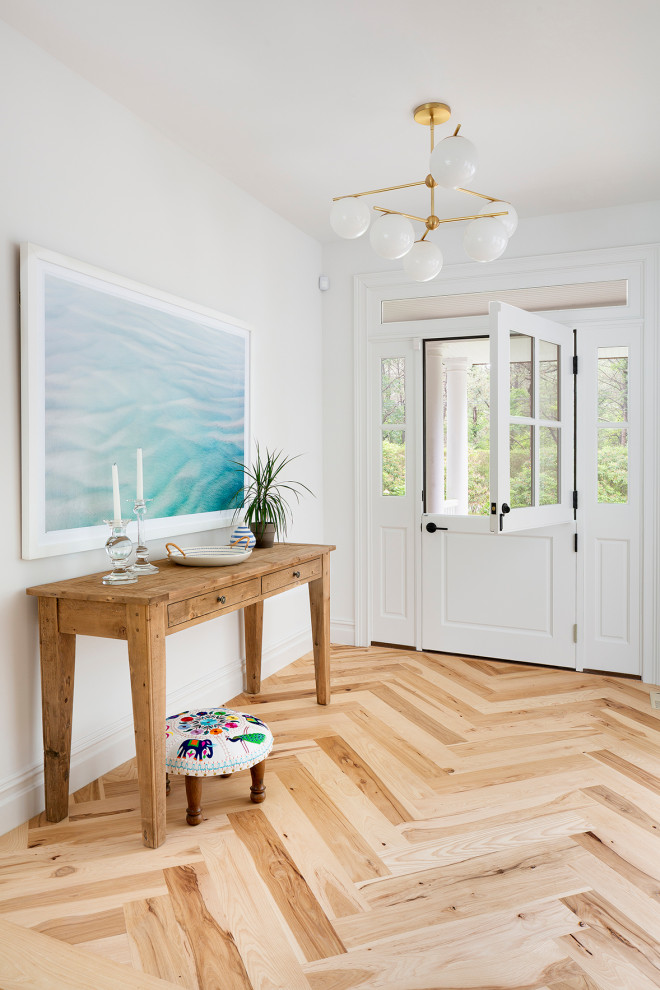 Photo of a beach style foyer in New York with white walls, light hardwood floors, a dutch front door, a white front door and beige floor.