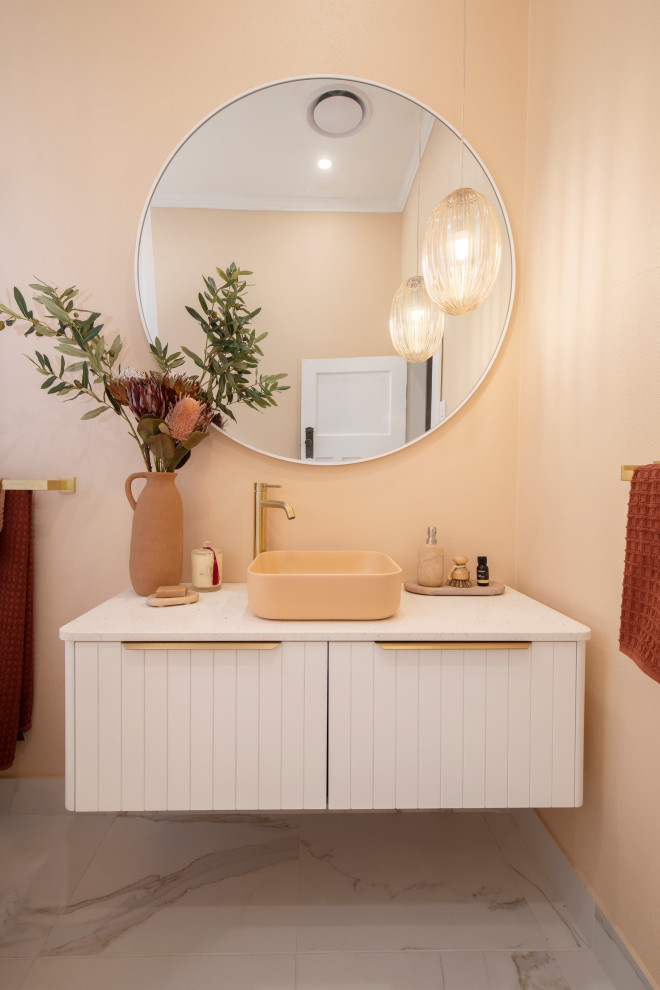 Exempel på ett litet modernt vit vitt en-suite badrum, med vita skåp, ett fristående badkar, en dusch/badkar-kombination, en toalettstol med hel cisternkåpa, orange kakel, keramikplattor, orange väggar, marmorgolv, ett fristående handfat, bänkskiva i kvarts, vitt golv och dusch med duschdraperi
