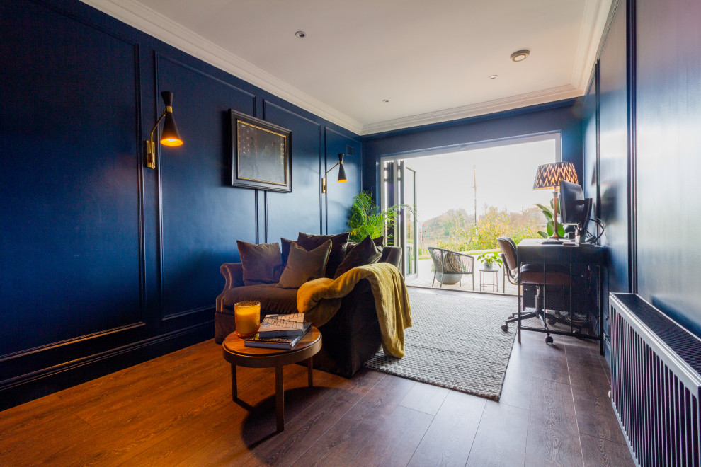 This is an example of a mid-sized contemporary study room in Dublin with blue walls, dark hardwood floors, a freestanding desk and panelled walls.