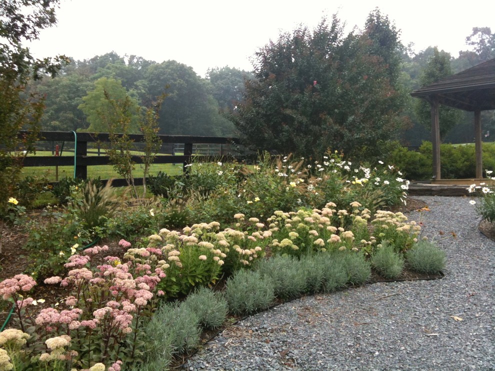 This is an example of a large rustic partial sun backyard stone formal garden for summer.