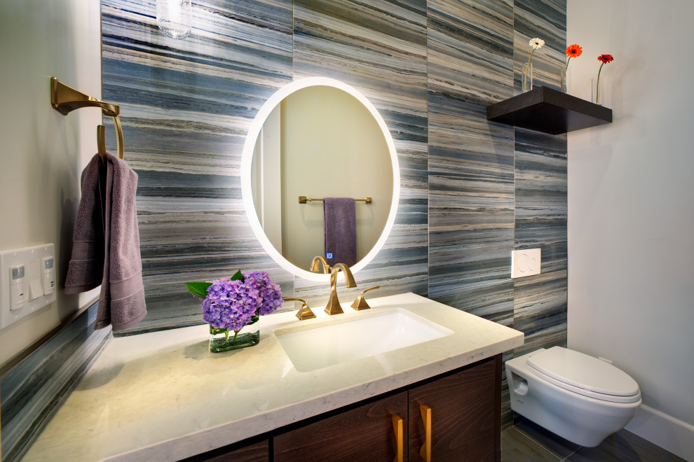 Design ideas for a mid-sized transitional powder room in Sacramento with flat-panel cabinets, brown cabinets, a wall-mount toilet, blue tile, porcelain tile, beige walls, porcelain floors, an undermount sink, engineered quartz benchtops, grey floor, beige benchtops and a built-in vanity.