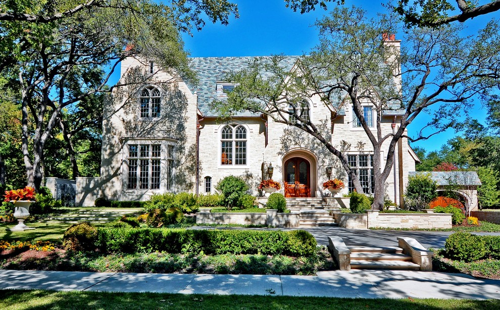 Large traditional two-storey beige house exterior in Dallas with stone veneer, a gable roof and a shingle roof.
