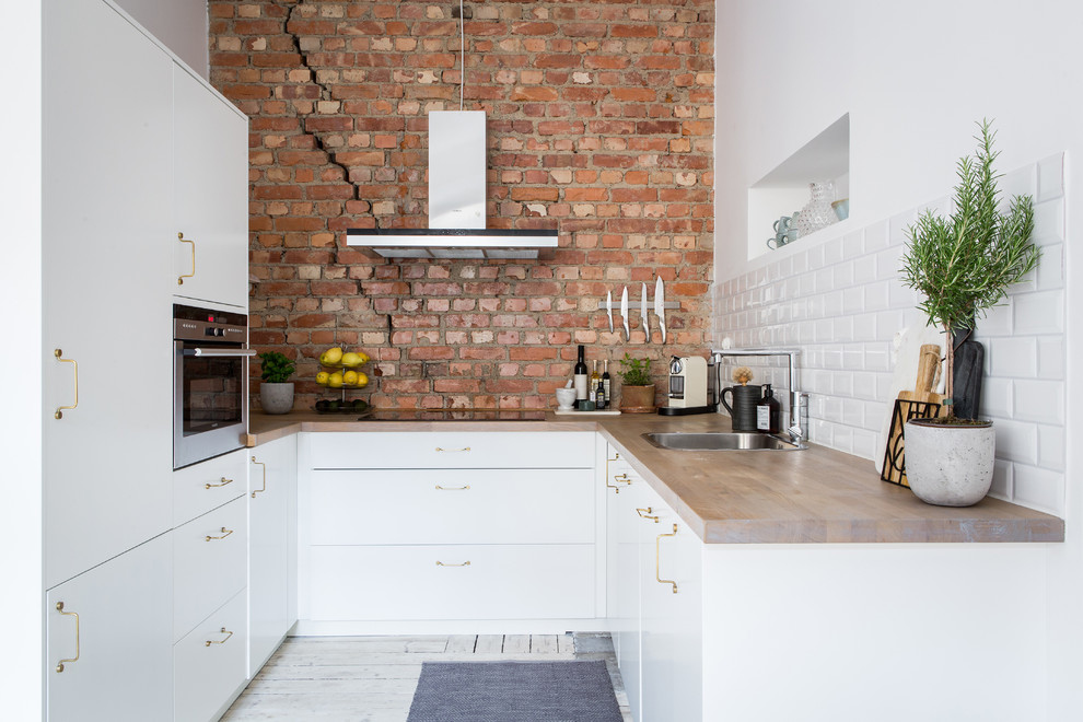 Design ideas for a scandinavian l-shaped separate kitchen in Gothenburg with a drop-in sink, flat-panel cabinets, white cabinets, wood benchtops, white splashback, subway tile splashback, stainless steel appliances, painted wood floors, no island and white floor.