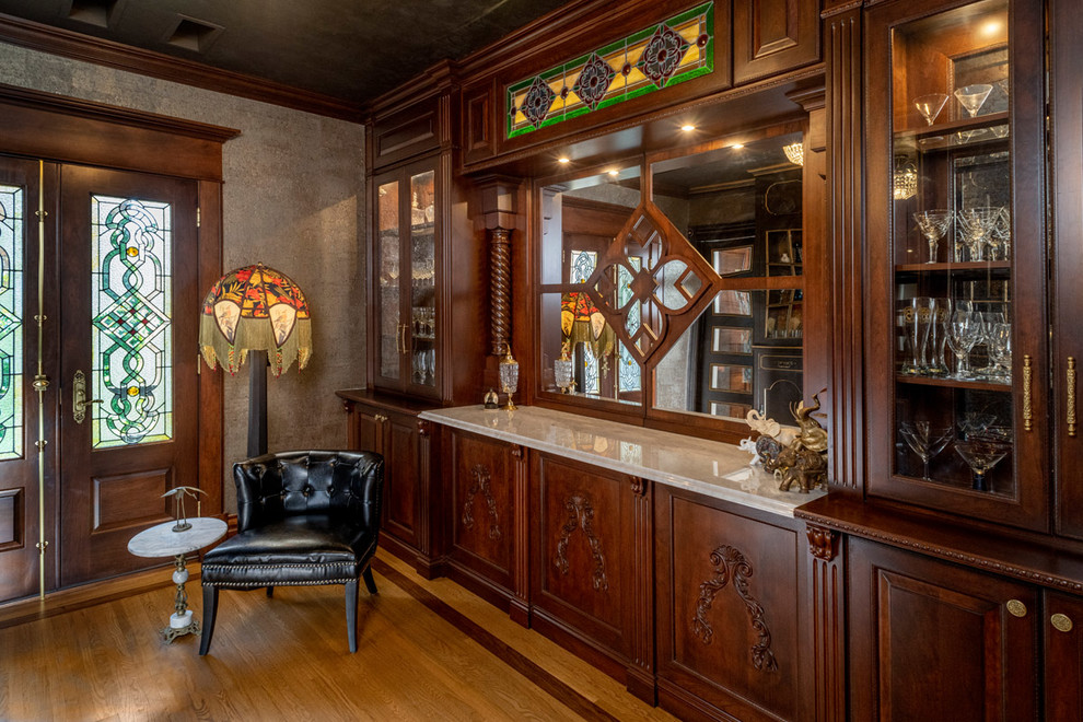 Design ideas for a mid-sized traditional single-wall wet bar in Other with a drop-in sink, medium wood cabinets, marble benchtops, medium hardwood floors, brown floor and brown benchtop.