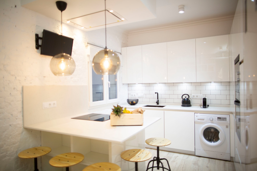 Photo of a mid-sized modern l-shaped separate kitchen in Madrid with a farmhouse sink, white cabinets, tile benchtops, black splashback, black appliances, ceramic floors, a peninsula, brown floor and white benchtop.