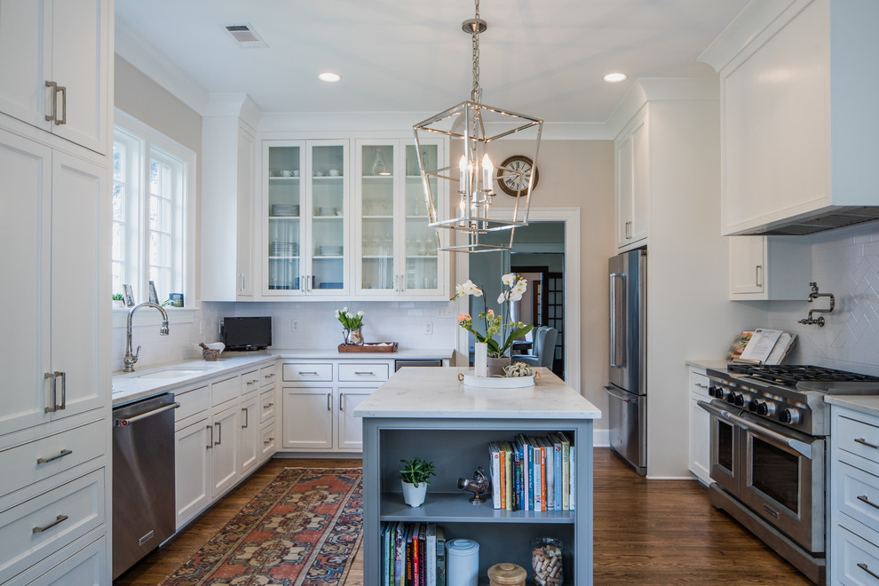 Photo of a mid-sized traditional u-shaped eat-in kitchen in Jackson with shaker cabinets, white cabinets, marble benchtops, white splashback, subway tile splashback, stainless steel appliances, medium hardwood floors, with island and brown floor.