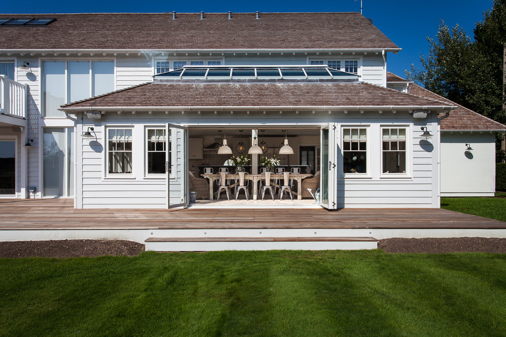 Inspiration for a large beach style two-storey white exterior in Sussex with wood siding.