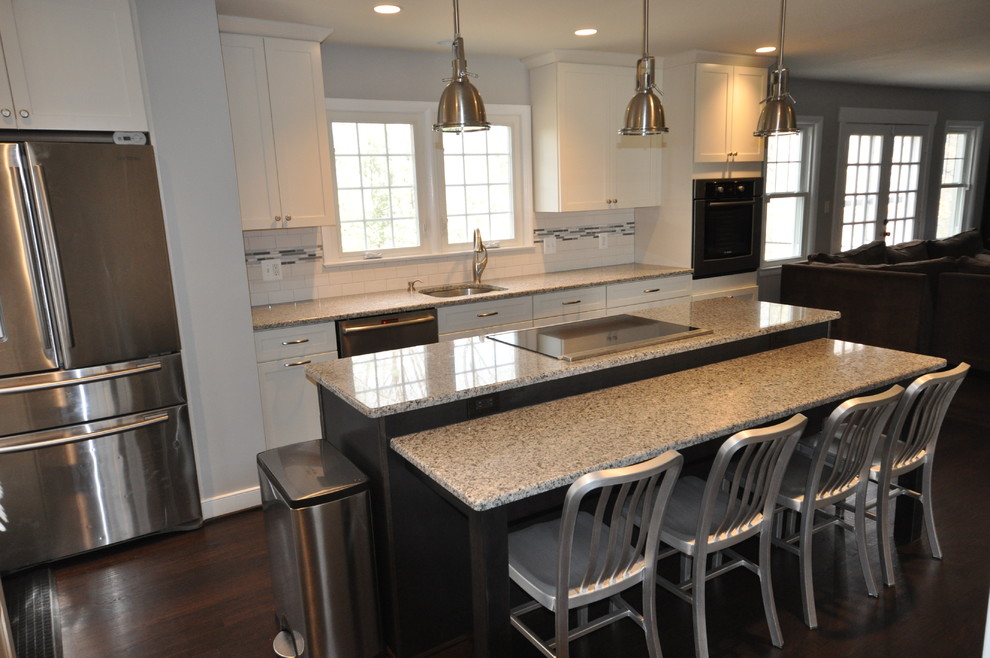 Example of a mid-sized transitional l-shaped dark wood floor and brown floor open concept kitchen design in DC Metro with an undermount sink, shaker cabinets, white cabinets, white backsplash, subway tile backsplash, stainless steel appliances and an island