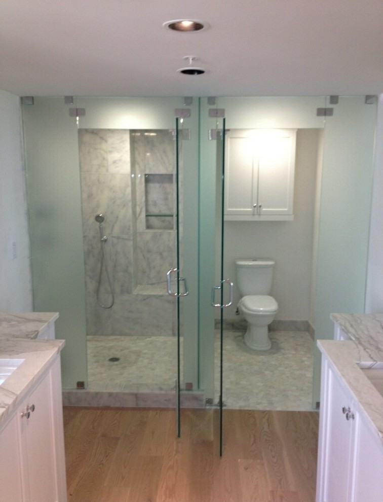 Inspiration for a mid-sized contemporary master bathroom in Tampa with shaker cabinets, white cabinets, an alcove shower, a one-piece toilet, white tile, marble, beige walls, light hardwood floors, an undermount sink and marble benchtops.