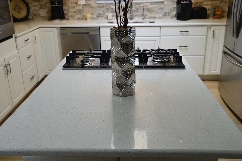 Enclosed kitchen - mid-sized transitional l-shaped porcelain tile enclosed kitchen idea in Albuquerque with an undermount sink, raised-panel cabinets, white cabinets, quartz countertops, beige backsplash, porcelain backsplash, stainless steel appliances and no island