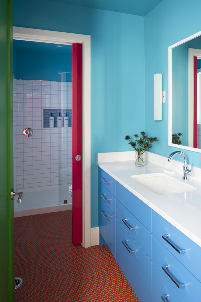 Stilmix Duschbad mit flächenbündigen Schrankfronten, blauen Schränken, Duschnische, blauer Wandfarbe, rotem Boden, weißer Waschtischplatte und eingebautem Waschtisch in Minneapolis
