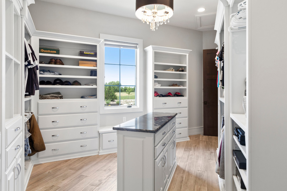 This is an example of an expansive transitional gender-neutral walk-in wardrobe in Kansas City with raised-panel cabinets, white cabinets, ceramic floors and white floor.