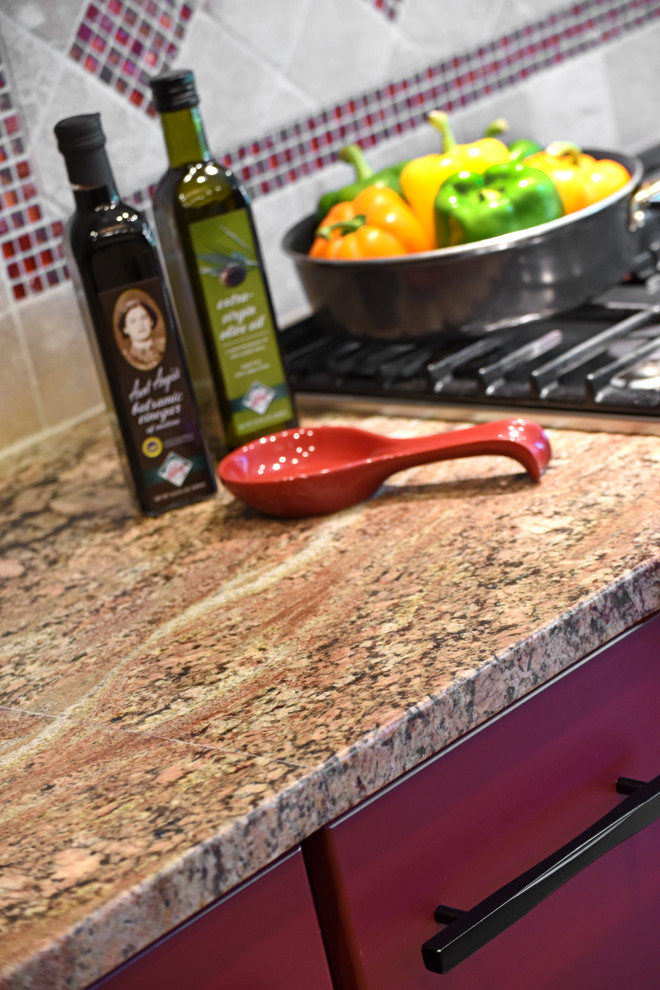 Inspiration for a large transitional porcelain tile and beige floor enclosed kitchen remodel with an undermount sink, flat-panel cabinets, red cabinets, granite countertops, beige backsplash, travertine backsplash, stainless steel appliances and an island