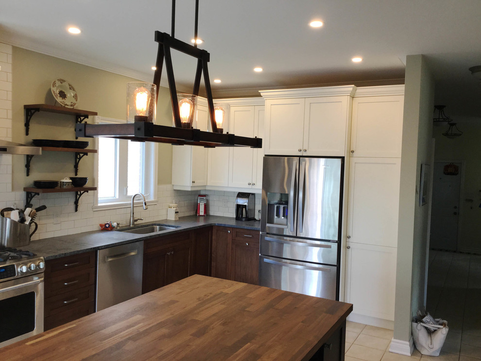 Example of a mid-sized transitional l-shaped kitchen design in Ottawa with an undermount sink, shaker cabinets, dark wood cabinets, soapstone countertops, white backsplash, ceramic backsplash, stainless steel appliances and an island