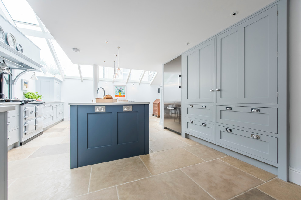 Large contemporary kitchen in Cornwall with a farmhouse sink, shaker cabinets, grey cabinets, quartz benchtops, metallic splashback, glass sheet splashback, panelled appliances, porcelain floors and with island.