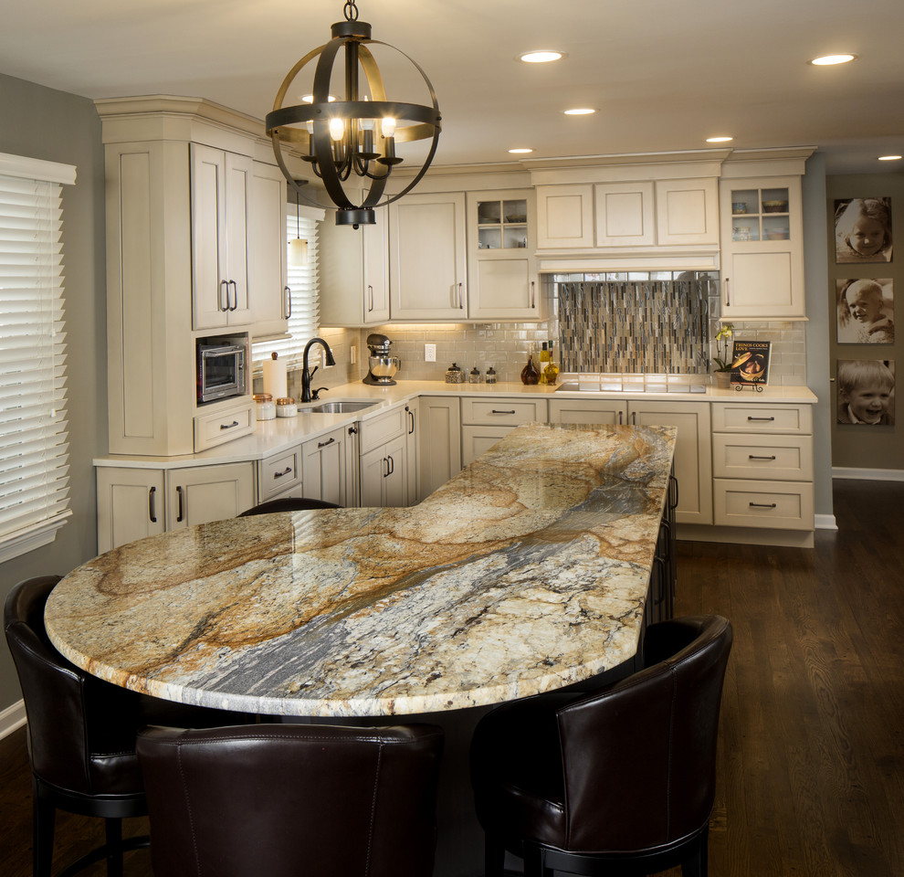 Example of a mid-sized transitional l-shaped dark wood floor eat-in kitchen design in Indianapolis with beige cabinets, granite countertops, beige backsplash, paneled appliances, an island, an undermount sink, shaker cabinets and ceramic backsplash