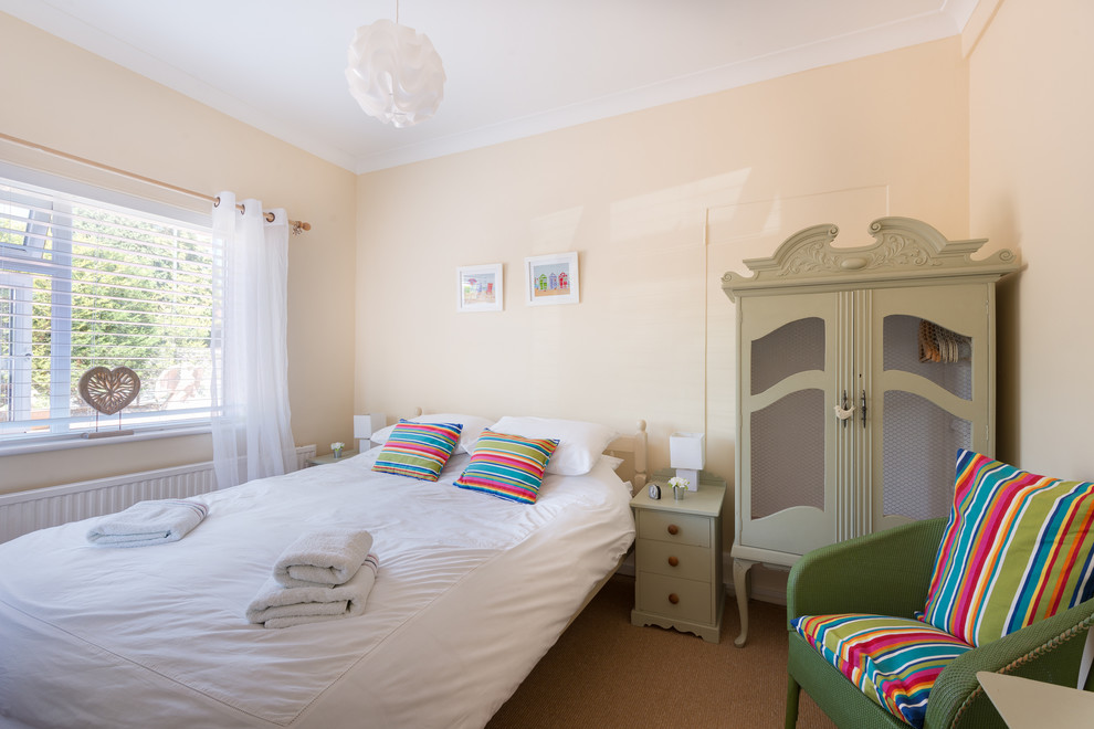 Photo of a mid-sized beach style guest bedroom in Devon with yellow walls and carpet.