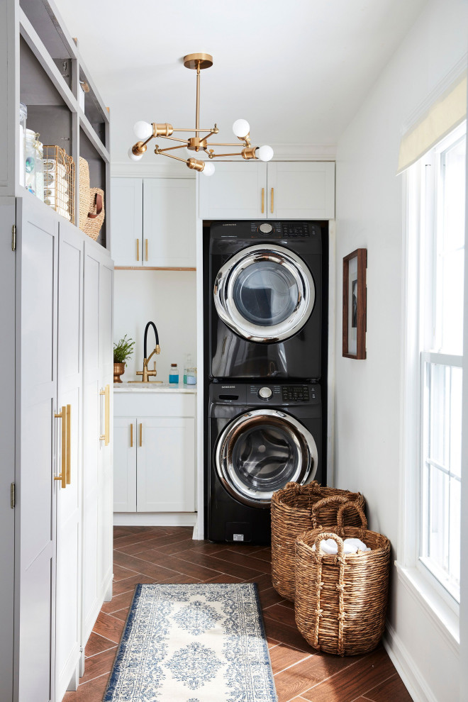 Laundry room - transitional l-shaped brown floor laundry room idea with recessed-panel cabinets, white cabinets, white walls and a side-by-side washer/dryer