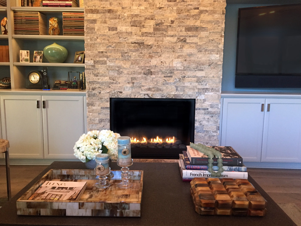 This is an example of a small arts and crafts open concept living room in Los Angeles with medium hardwood floors, a standard fireplace, a stone fireplace surround, a built-in media wall, blue walls and beige floor.