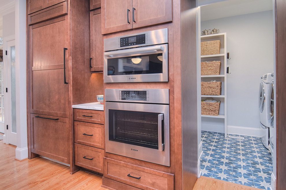 Open concept kitchen - huge transitional light wood floor open concept kitchen idea in Charlotte with a farmhouse sink, shaker cabinets, medium tone wood cabinets, quartzite countertops, an island and white countertops