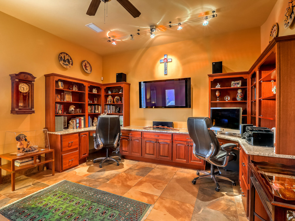 Large home office in Albuquerque with slate floors, a built-in desk, multi-coloured floor and orange walls.