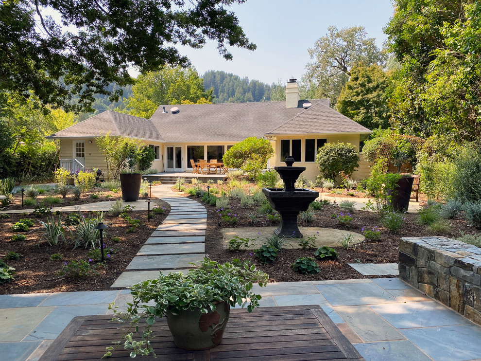 Cette image montre un grand jardin arrière traditionnel au printemps avec une exposition ensoleillée et des pavés en pierre naturelle.