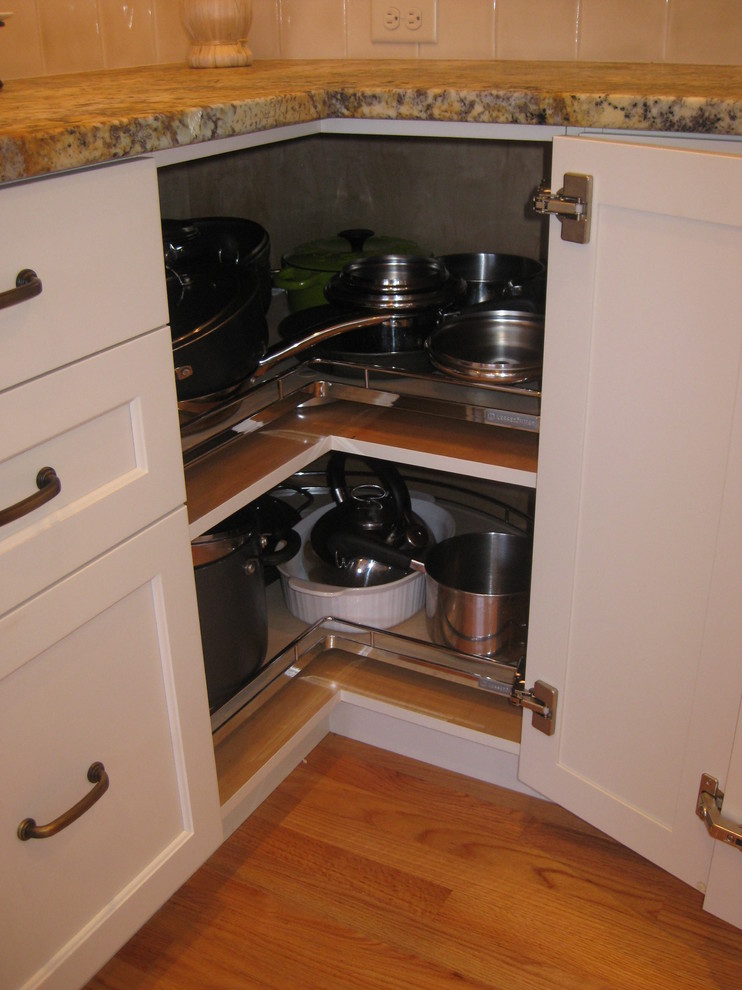 Mid-sized transitional l-shaped light wood floor open concept kitchen photo in Bridgeport with an undermount sink, shaker cabinets, white cabinets, granite countertops, white backsplash, porcelain backsplash, stainless steel appliances and an island