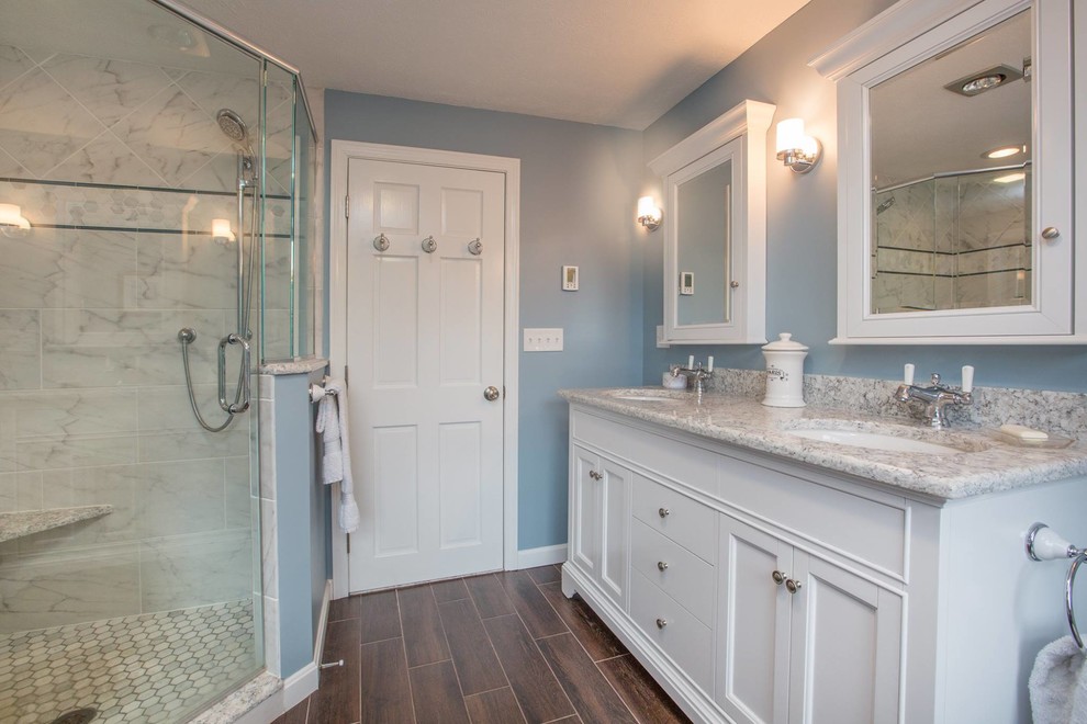 Design ideas for a mid-sized traditional master bathroom in Boston with shaker cabinets, white cabinets, a two-piece toilet, blue walls, an undermount sink, granite benchtops, a corner shower, a hinged shower door, gray tile, marble, dark hardwood floors, brown floor and grey benchtops.