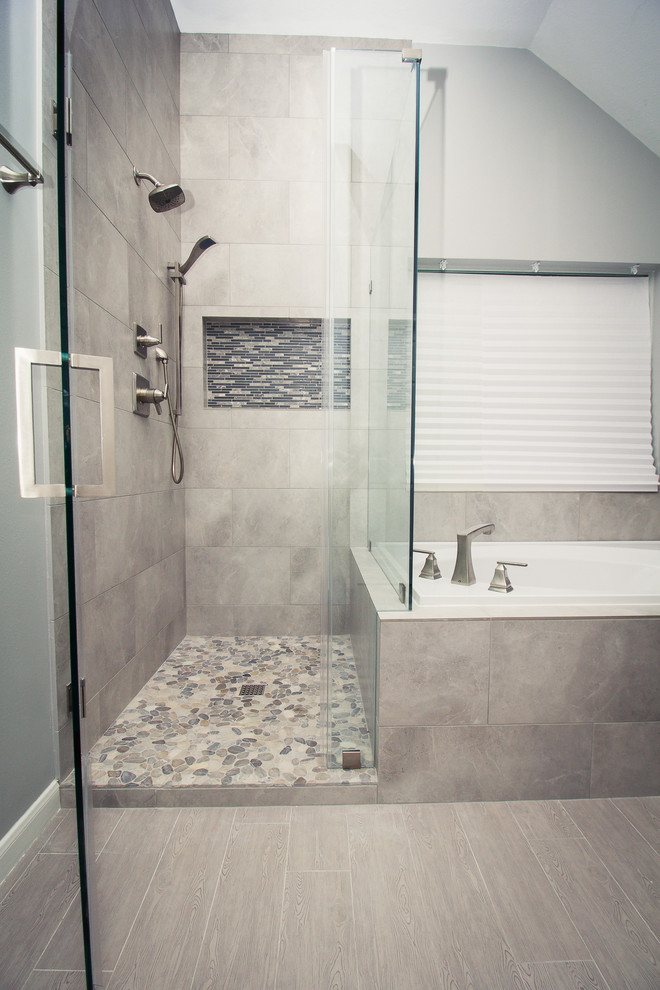 Photo of a mid-sized transitional master bathroom in Houston with dark wood cabinets, a drop-in tub, a corner shower, gray tile, porcelain tile, grey walls, porcelain floors, an undermount sink, engineered quartz benchtops, grey floor, a hinged shower door and beaded inset cabinets.