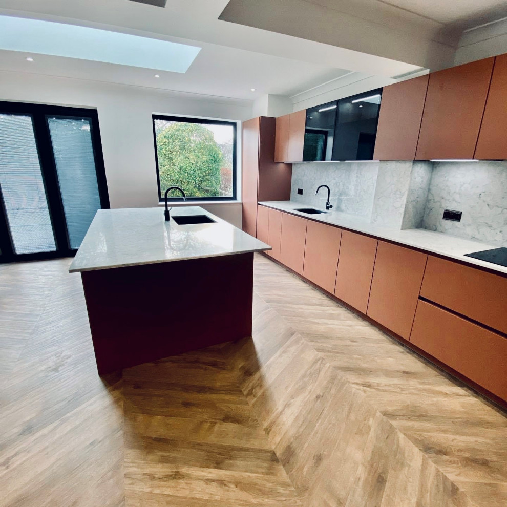 Photo of a mid-sized modern l-shaped eat-in kitchen in Essex with an integrated sink, flat-panel cabinets, red cabinets, granite benchtops, grey splashback, granite splashback, panelled appliances, vinyl floors, with island, brown floor, grey benchtop and vaulted.