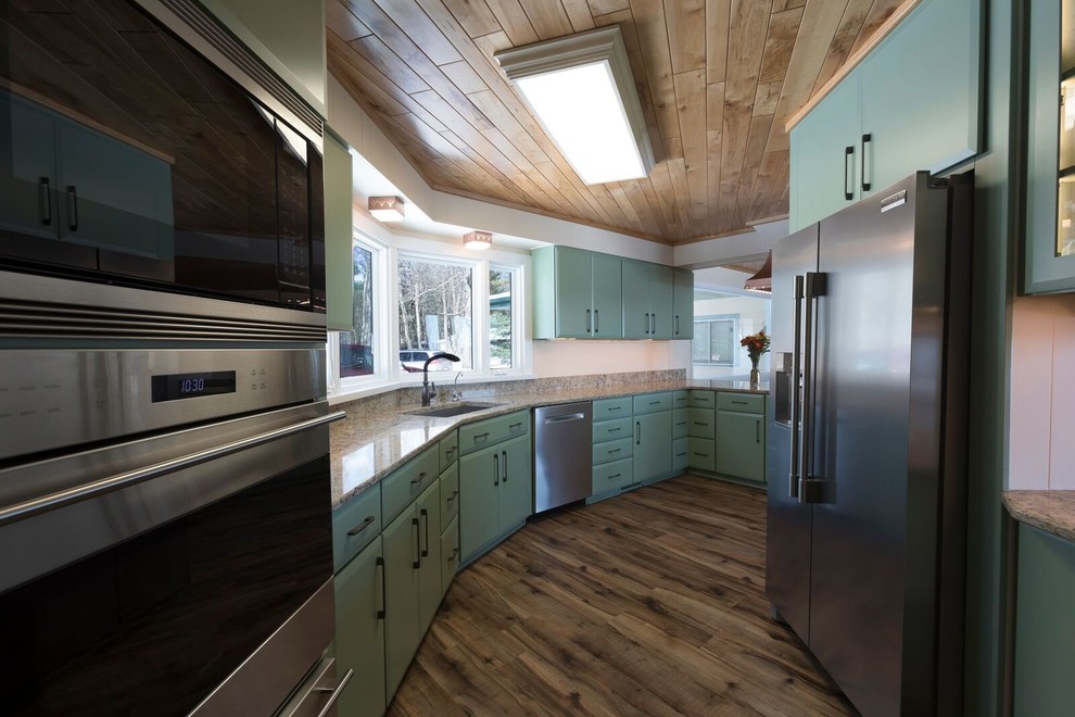 Mid-sized transitional l-shaped eat-in kitchen in Other with an undermount sink, flat-panel cabinets, green cabinets, quartz benchtops, stainless steel appliances, vinyl floors, a peninsula, brown floor and beige benchtop.