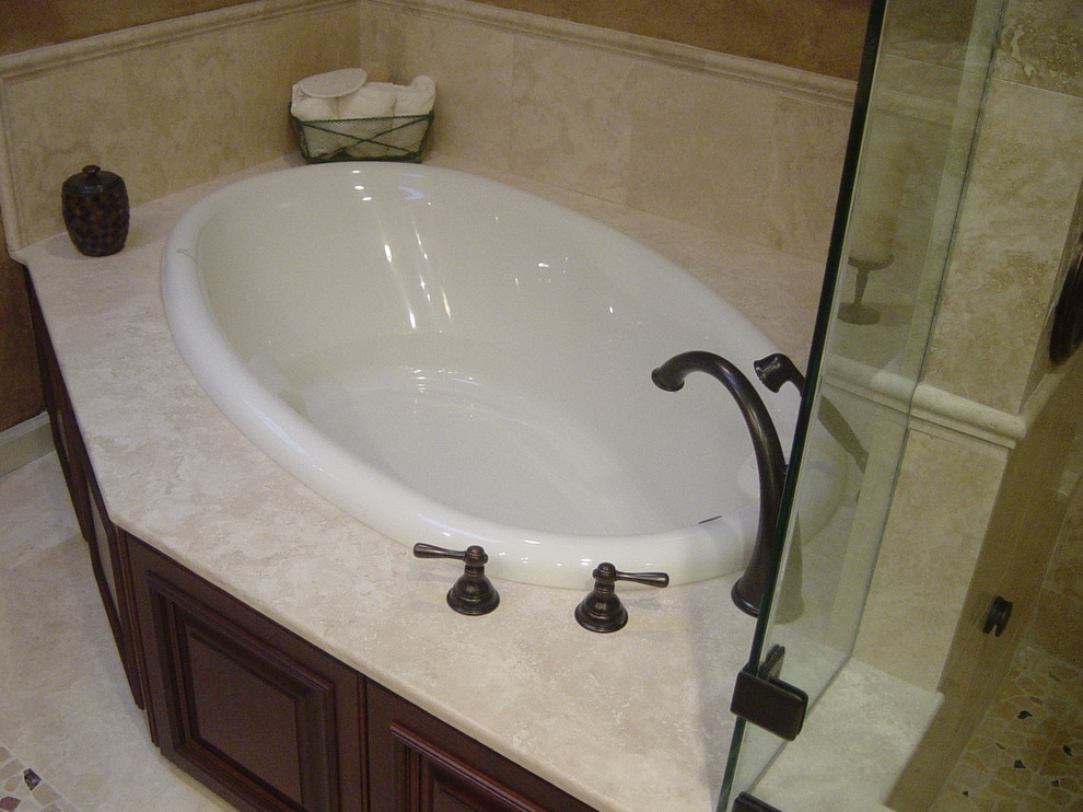 This is an example of a mid-sized traditional master bathroom in Boston with a drop-in tub and travertine floors.