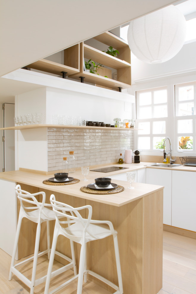 Design ideas for a scandinavian u-shaped kitchen in Madrid with a drop-in sink, flat-panel cabinets, white cabinets, wood benchtops, white splashback, light hardwood floors, a peninsula, beige floor and beige benchtop.