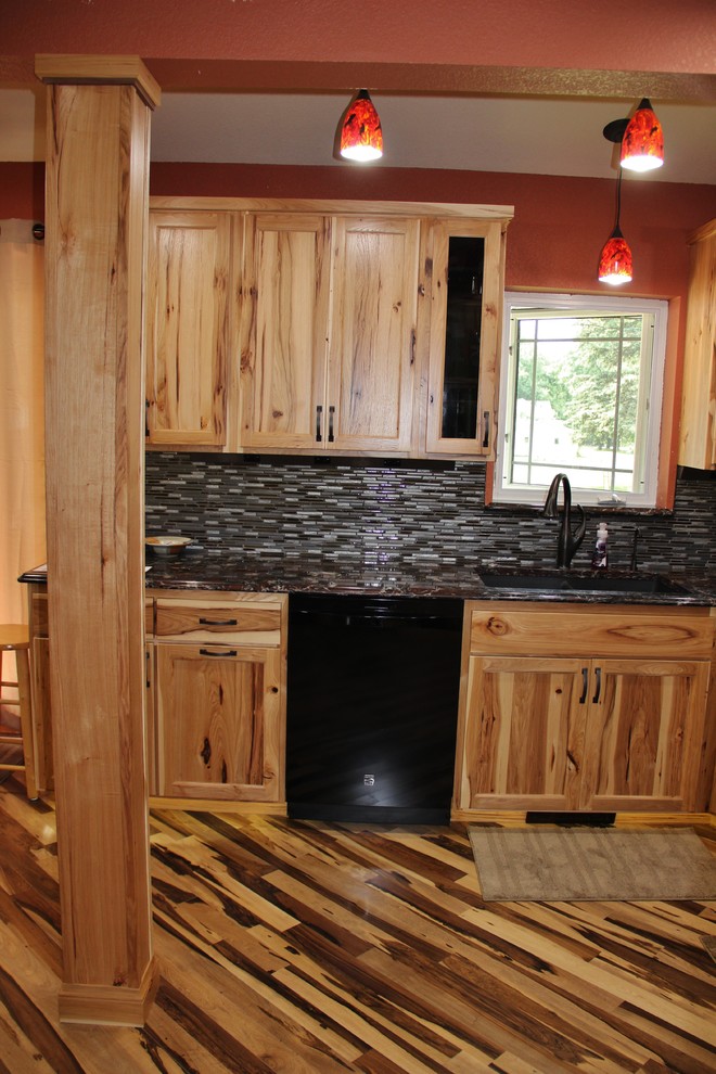 Inspiration for a large rustic l-shaped medium tone wood floor eat-in kitchen remodel in Minneapolis with an undermount sink, flat-panel cabinets, light wood cabinets, quartz countertops, black backsplash, glass tile backsplash, black appliances, red walls and no island